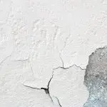 Modern bathroom with a freestanding bathtub, double vanity, large mirror, and tiled walls under bright overhead lighting.